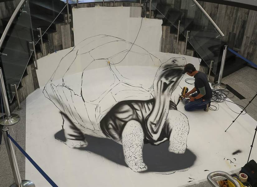Un artista dibuja una tortuga en un centro comercial de Quito.