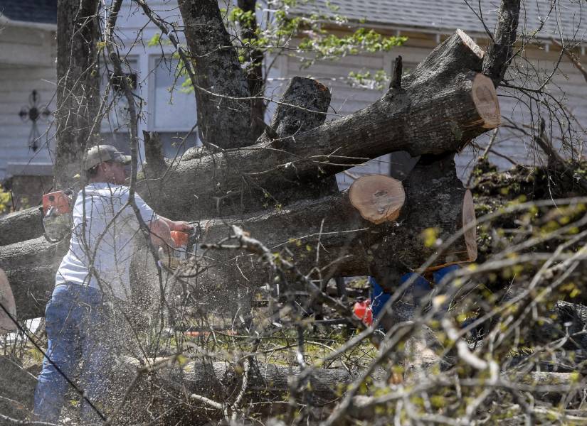 Un residente trabaja para despejar un árbol caído del frente de una casa el día después de que un tornado azotara Amory, Mississippi, EE. UU.
