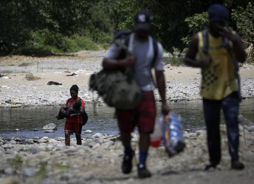 Migrantes de Haití cruzan el río Tuquesa tras ser trasladados en canoa.