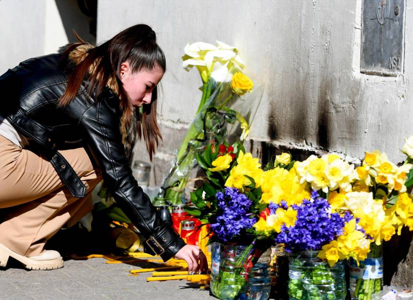 Una mujer enciende una vela en un monumento improvisado en memoria de un niño que falleció tras sufrir graves heridas en la tragedia de la estación de tren de Novi Sad en noviembre de 2024.
