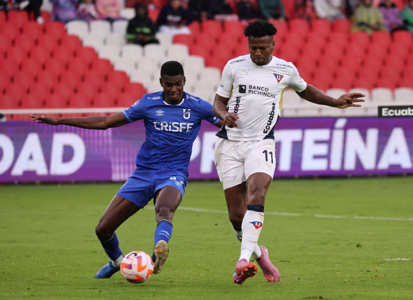 El delantero de Liga de Quito, Michael Estrada, disputa el balón contra Carlos Medina, Universidad Católica