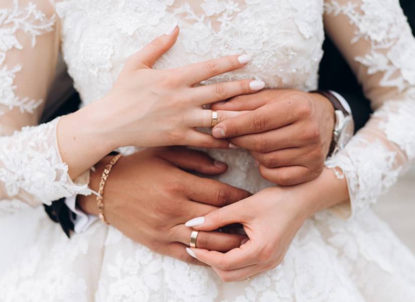 Pareja en su boda mostrando sus anillos de compromiso.