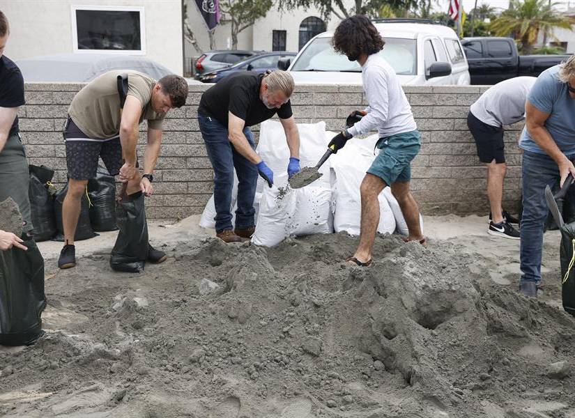 Familias reuniendo arena para fortalecer sus hogares.