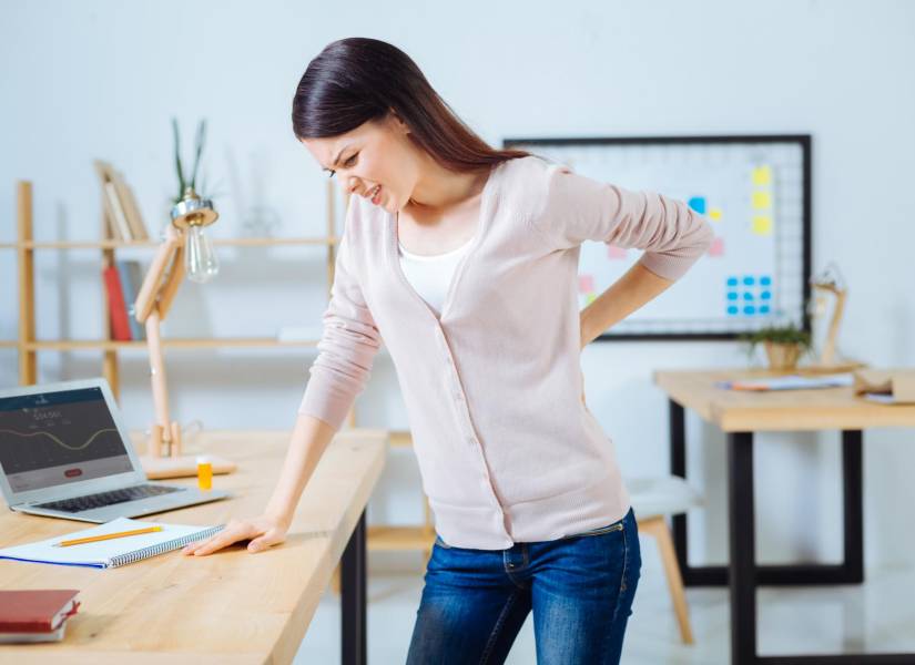Mujer con dolor de espalda en la oficina.