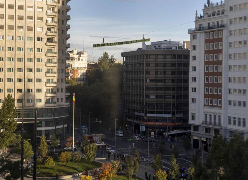 Una activista de Greenpeace recorre una cinta suspendida a 30 metros de altura en pleno centro de Madrid.