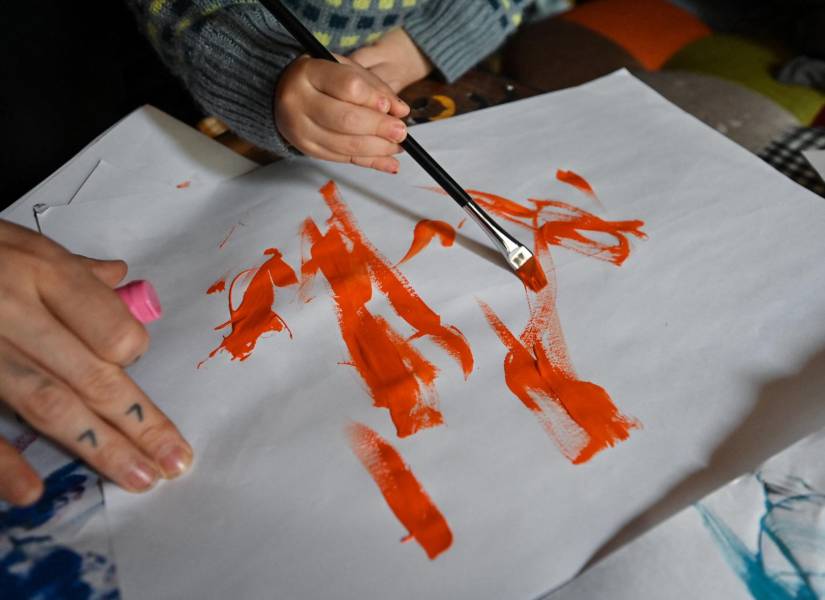Esta foto, tomada el 8 de abril de 2025, muestra a la artista de 21 meses Pulgarcita (derecha) usando un pincel para pintar junto a su madre (izquierda) en el hogar familiar en Tokio.