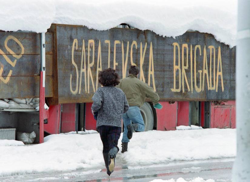 Una pareja corre buscando un refugio para evitar ser disparados durante le guerra de Bosnia. Foto tomada un 28 de marzo de 1993.