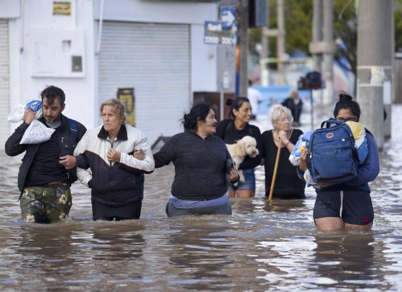 Personas caminan a través de las calles inundadas al día siguiente de una fuerte tormenta en Bahía Blanca, a 600 km al sur de Buenos Aires, el 8 de marzo de 2025.