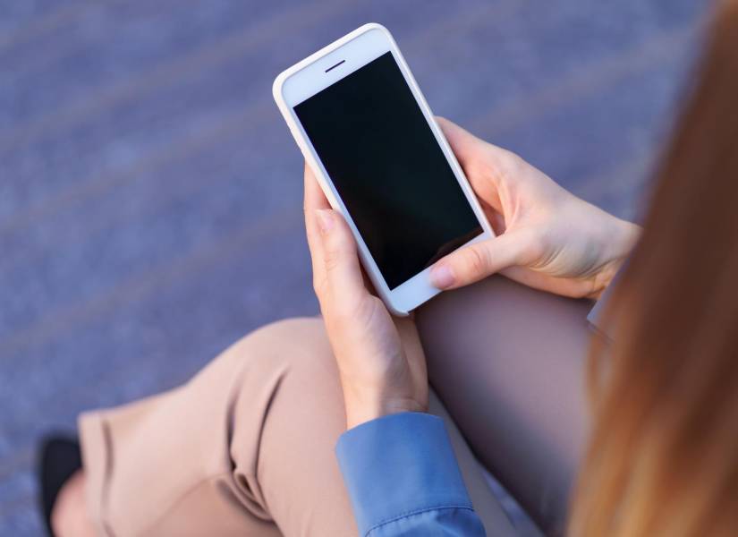 Mujer sosteniendo un teléfono apagado