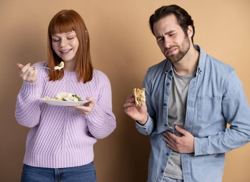 Pareja alimentándose, uno con dolor estomacal.