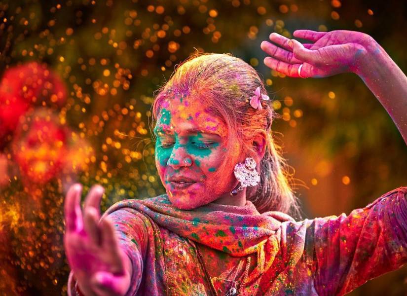 Mujer hindú cubierta de polvo de color hecho a base de maíz, bailando.