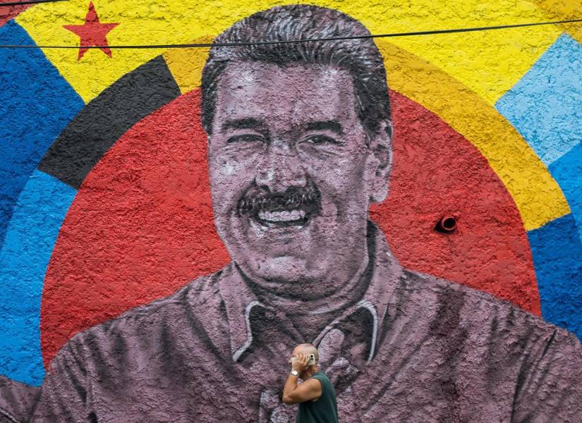 Una persona camina frente a un mural con la imagen del presidente de Venezuela, Nicolás Maduro, durante una manifestación este viernes, en Caracas (Venezuela).