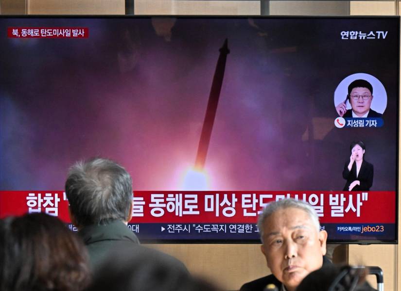 La gente al rededor de un televisor mirando las noticias con un video de una prueba de misiles de Corea del Norte.