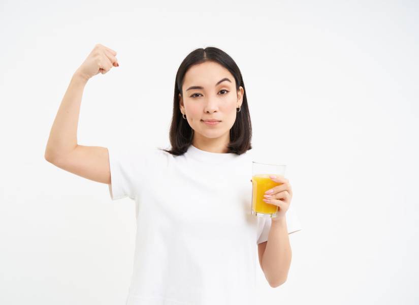 Mujer mostrando fuerza con un vaso de jugo
