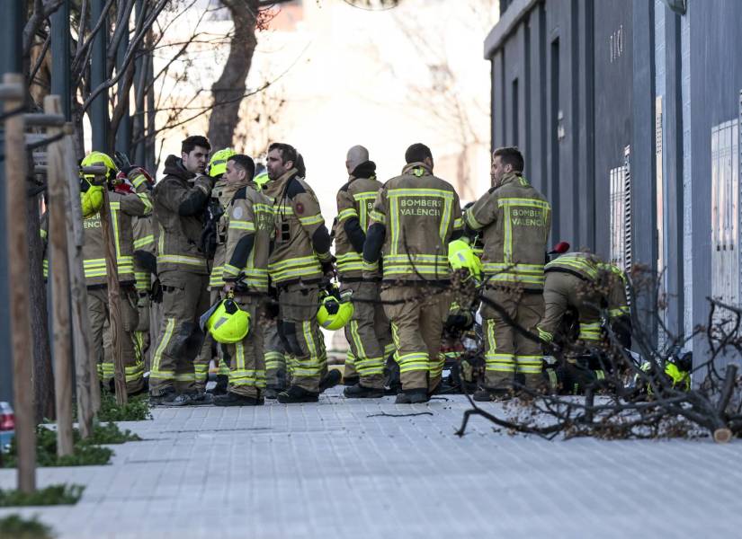 Varios bomberos esperan cerca de los edificios destruidos un día después de que un incendio arrasara dos bloques de apartamentos.