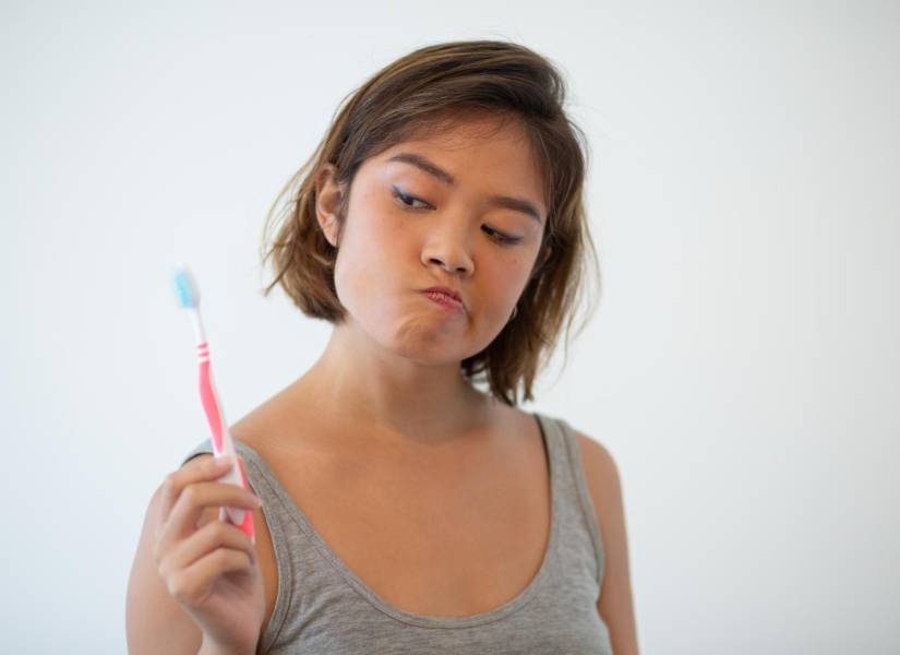 Mujer con cepillo de dientes dudoso.