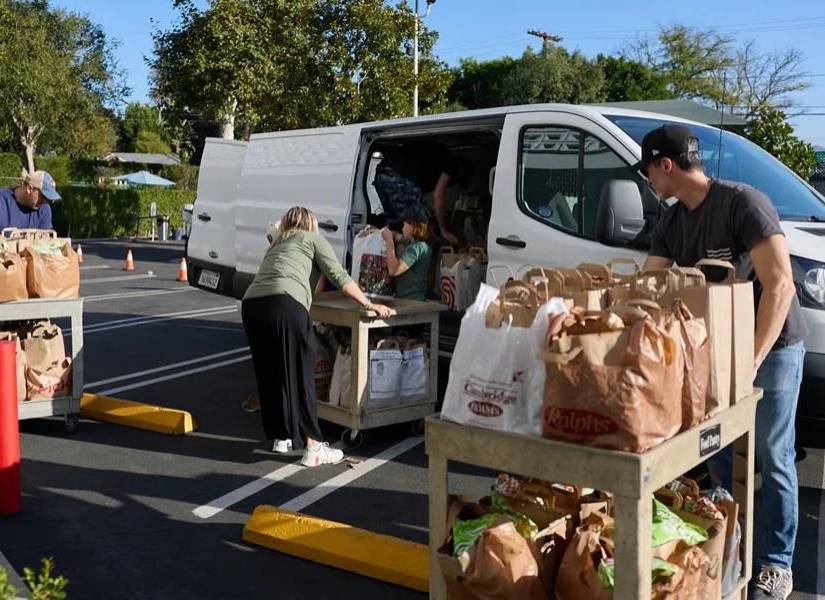 Personas con bolsas llenas de alimentos para donación.