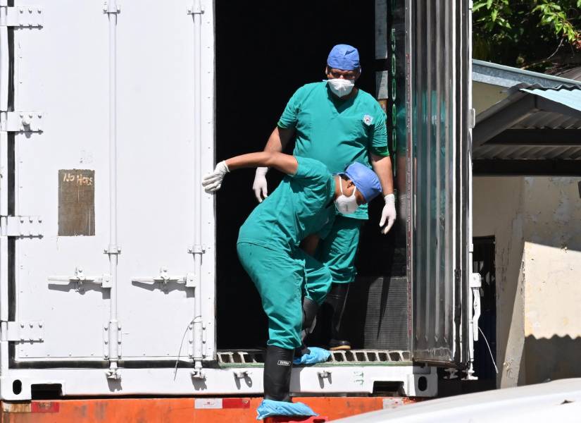 Funcionarios estatales bajan de un camión en el que se trasladan cuerpos hallados en el Darién.