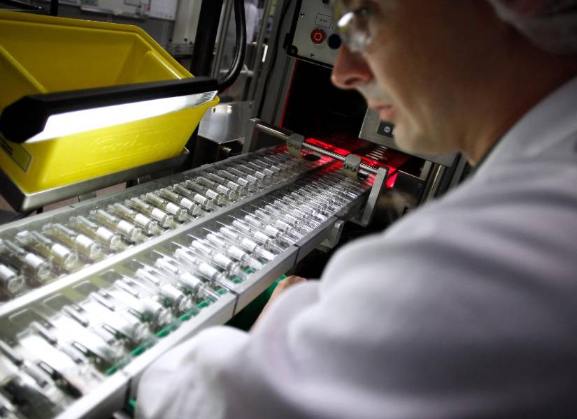 Imagen de un empleado trabajando en una línea de producción de vacunas contra la influenza.