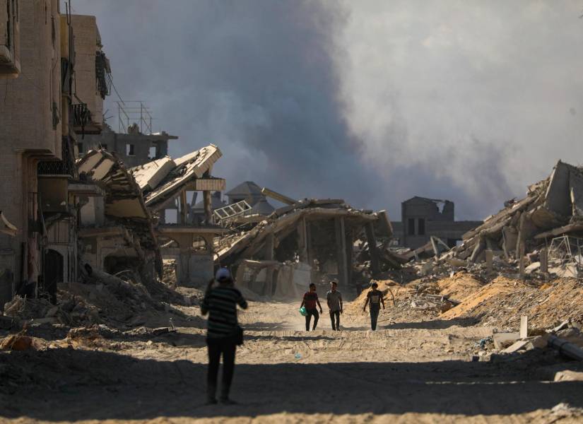 Palestinos caminan por una calle destruída por los bombardeos israelíes en Gaza.