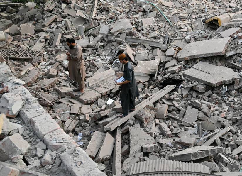 Los lugareños permanecen sobre los escombros de las estructuras destruidas en el complejo sanitario y educativo del Gobierno en Muridke, a unos 30 kilómetros de Lahore, el 7 de mayo de 2025, después de los ataques indios.