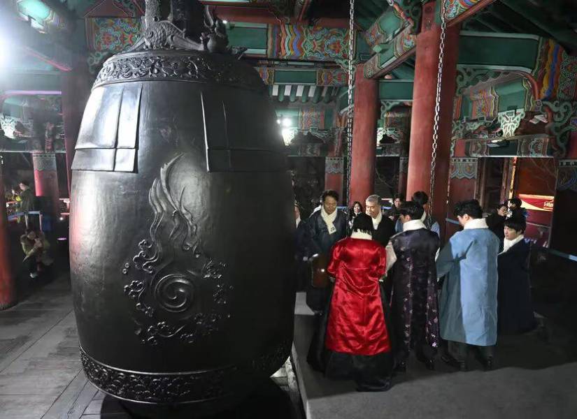 Funcionarios japoneses realizando la ceremonia tradicional de hacer sonar una gran campana en un templo.