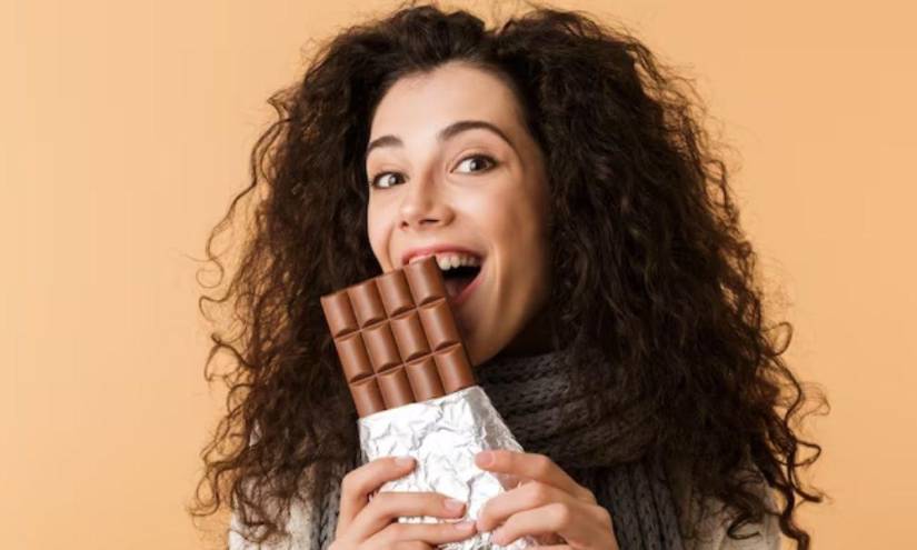 Imagen referencial de una chica comiendo una barra de chocolate, uno de los alimentos que podría perjudicar nuestra calidad de sueño, según un estudio publicado por BBC News.